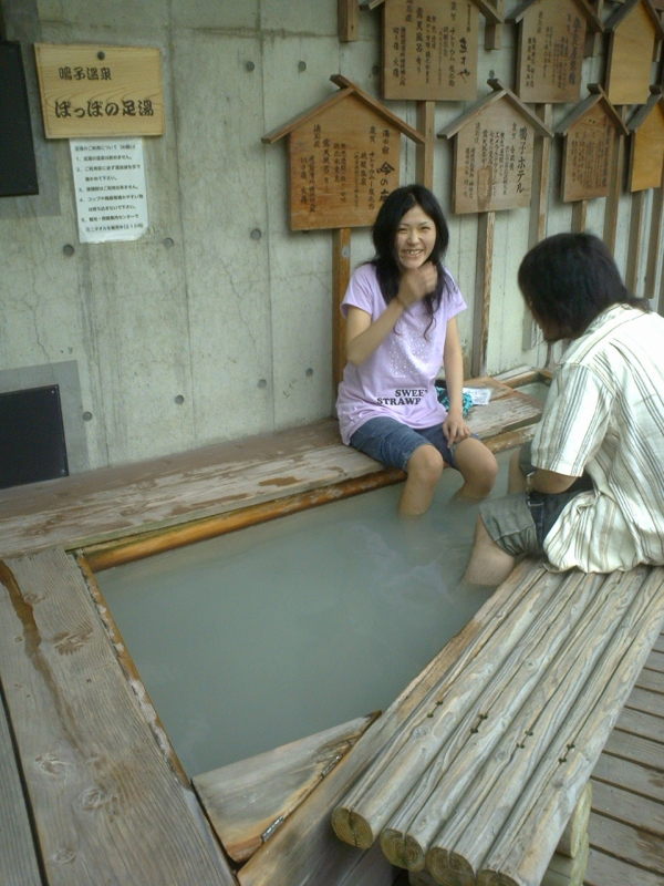 A couple shares a giggle while soaking their feet in Naruko Station's ashiyu.